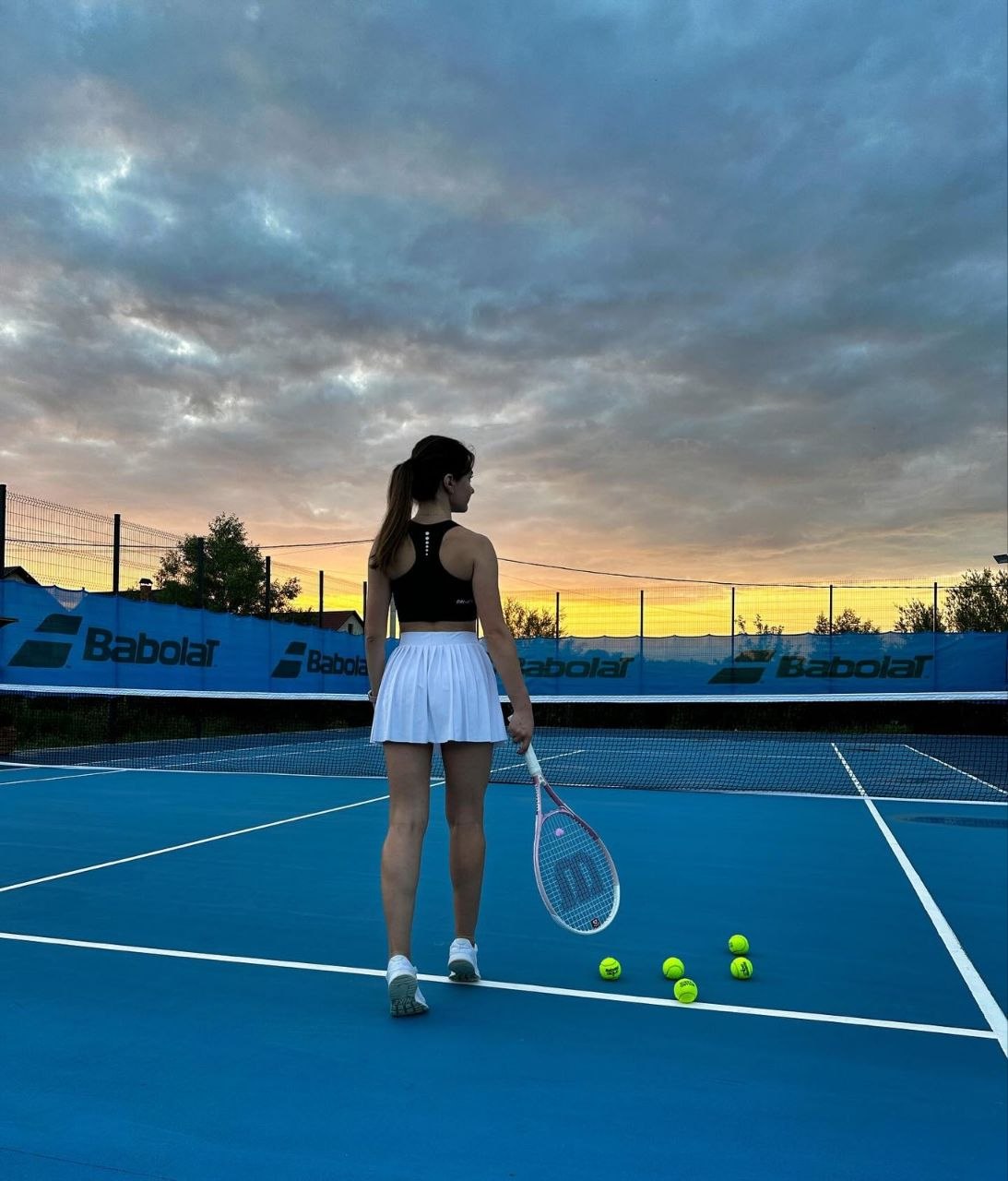 Tennis player on blue court at sunset